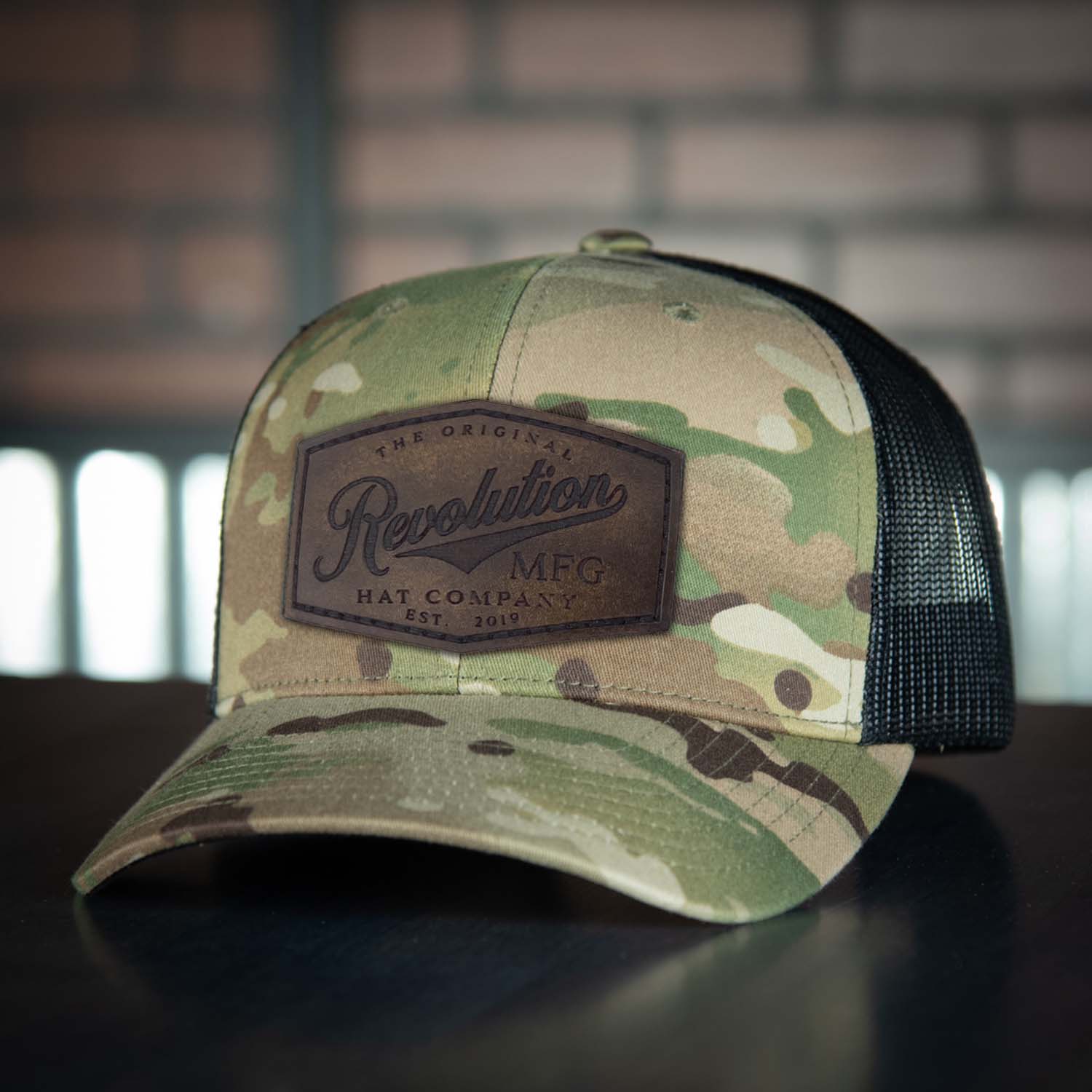 Revolution Mfg Hat Co full grain leather patch on a classic multicam camo trucker hat with black mesh