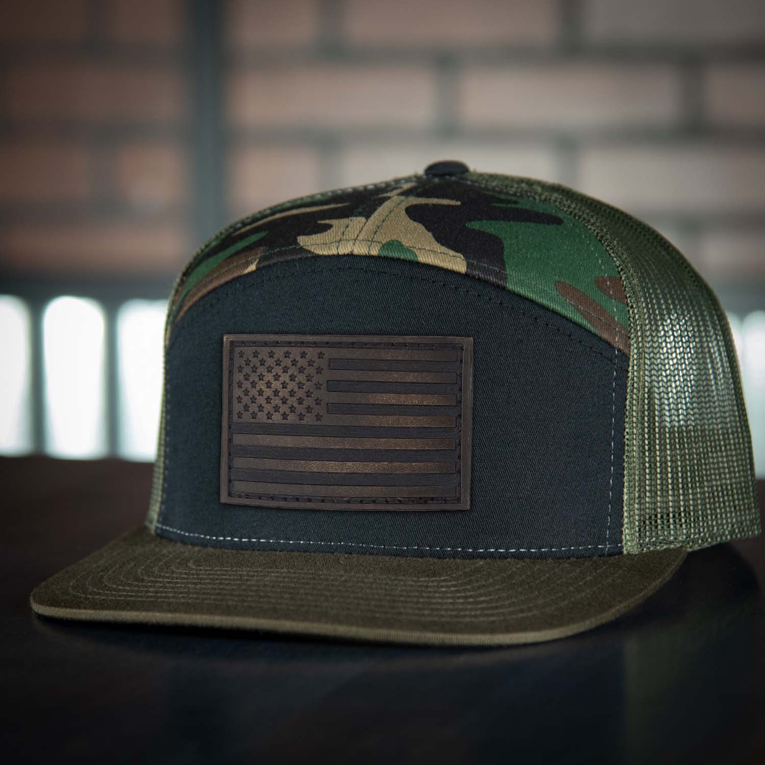 Revolution Mfg full grain leather American flag patch on a 7 panel trucker hat in woodland with a black front panel and loden mesh