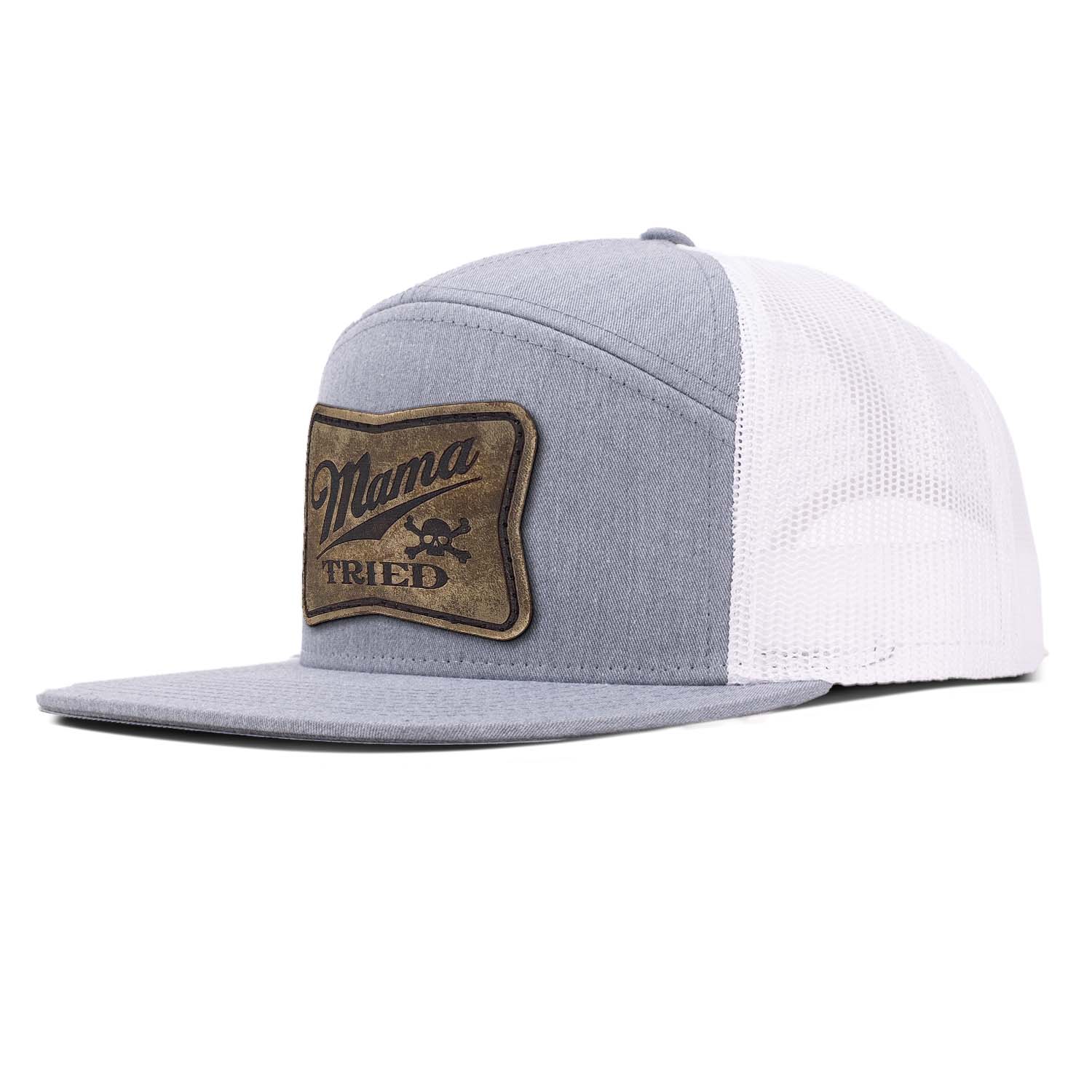 A heather gray 7 panel trucker hat with white mesh featuring our full grain leather vintage finish Mama Tried patch stitched on the seamless front panel