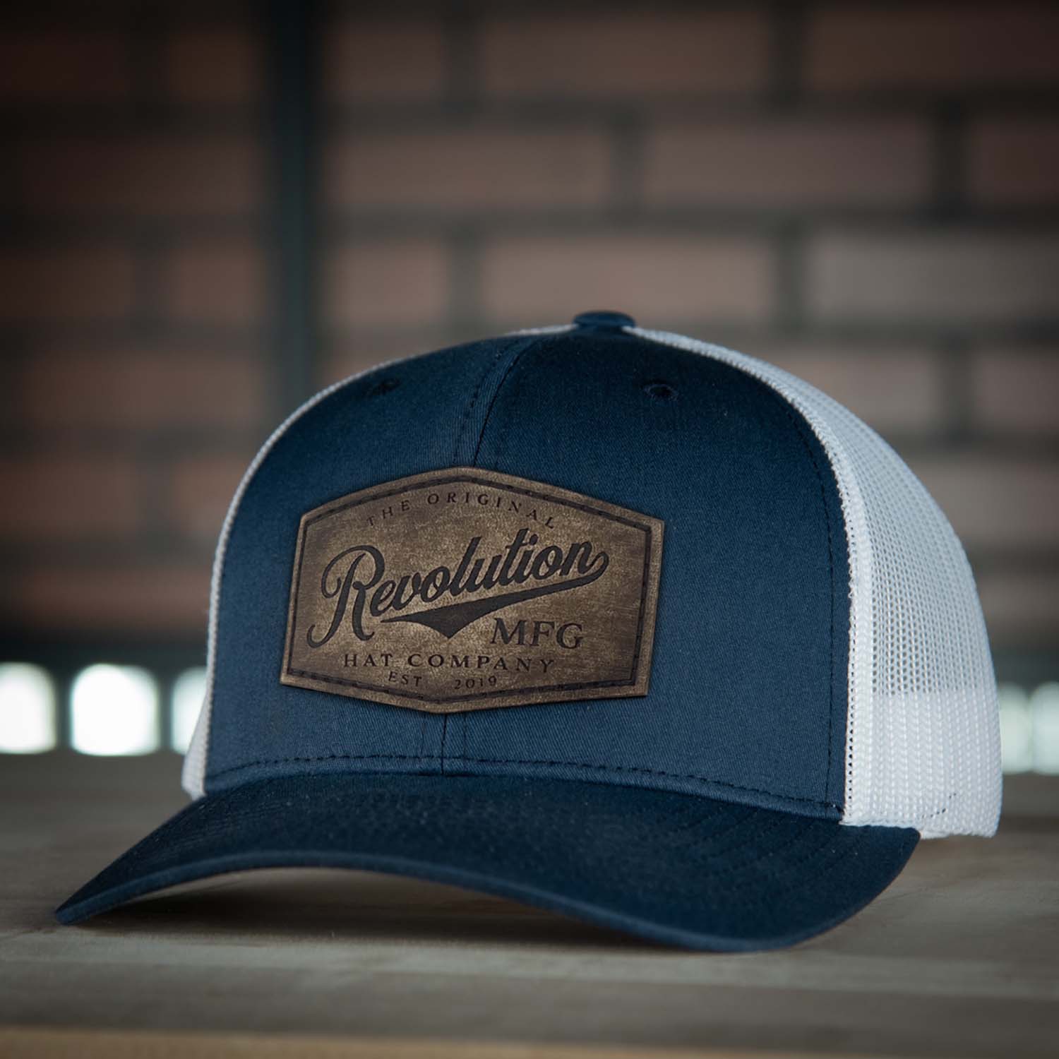 Revolution Hat Co full grain leather patch in a vintage finish on a navy with white mesh classic trucker hat