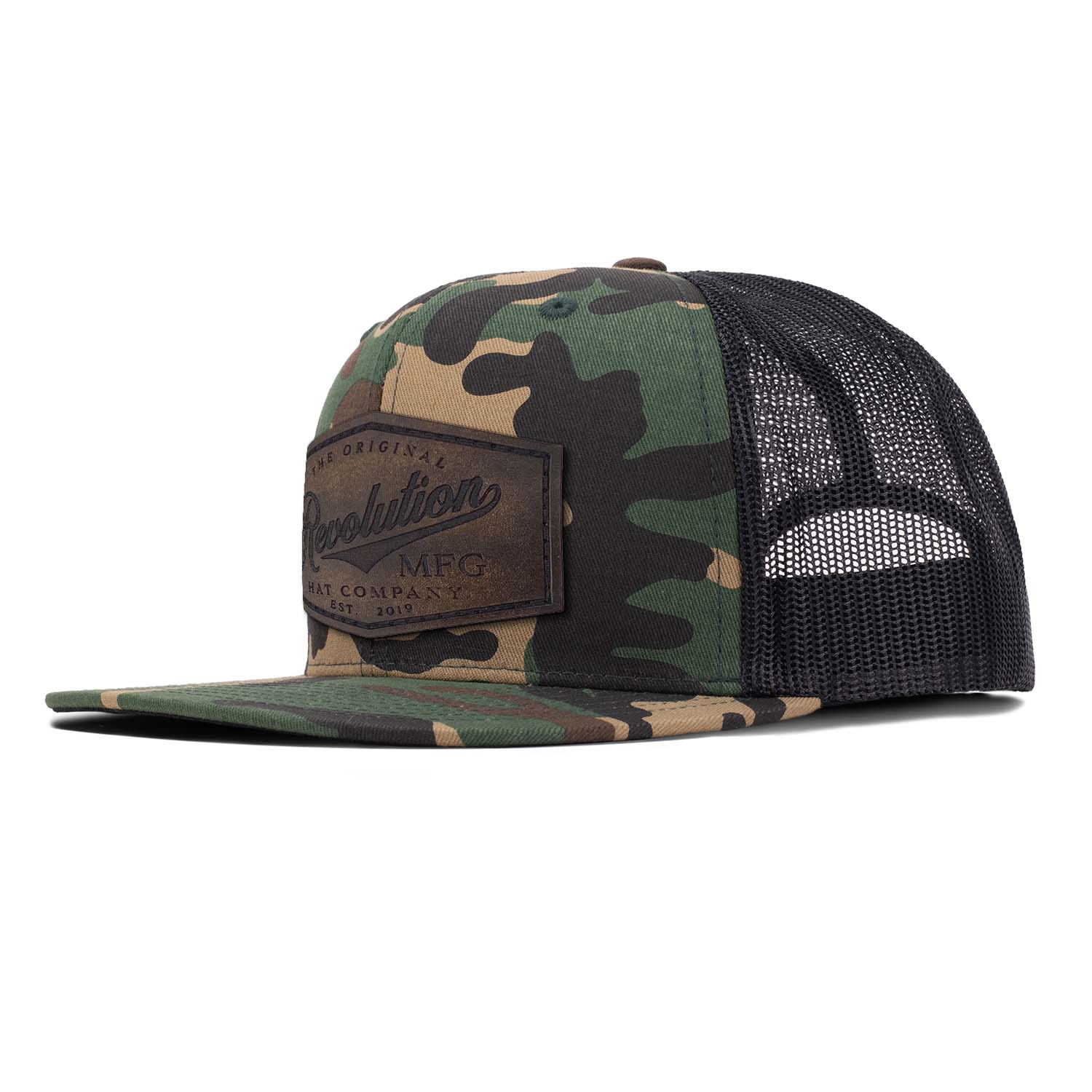 Revolution Mfg flat bill trucker hat in woodland camo and black mesh with a brown full grain leather Revolution Hat Co patch