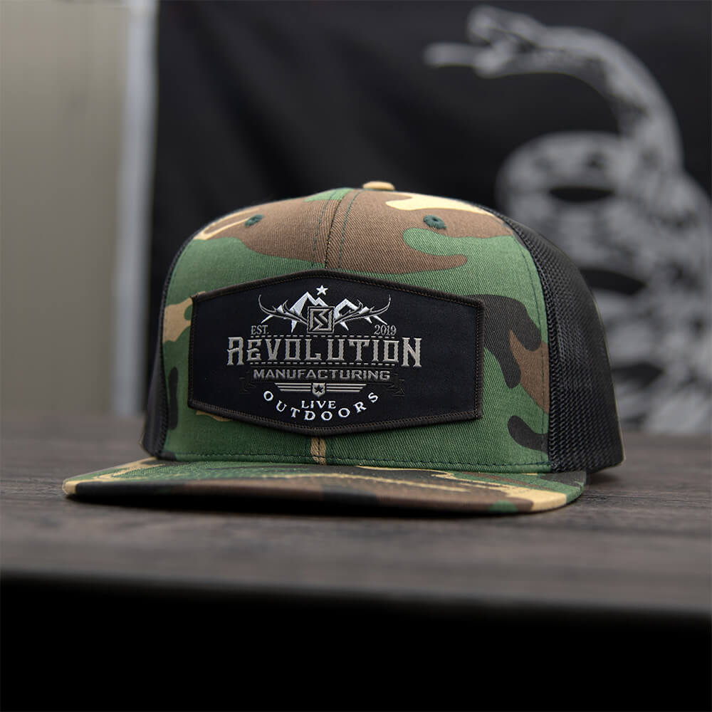 Classic flat bill trucker hat in woodland camo with black mesh with Revolution Mfg Live Outdoors woven patch