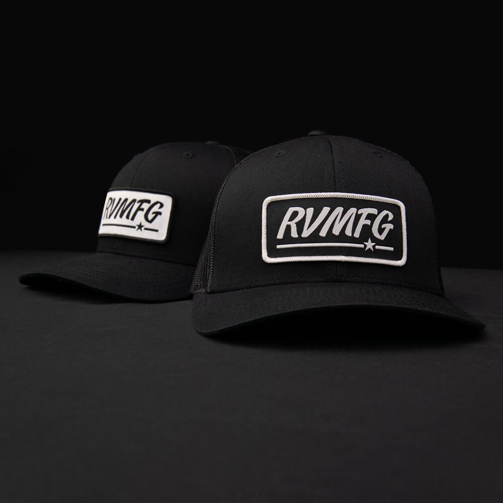 All black classic trucker patch hat featuring a woven RVMFG patch in either black or white background